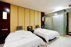 Habitación de hotel con dos camas, un espejo grande y un cabecero de madera.