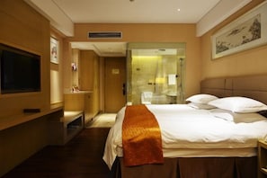 A hotel room with a bed, a television, a bathroom with a glass partition, and a painting on the wall. - Richun Teaism Hotel (Quanzhou)