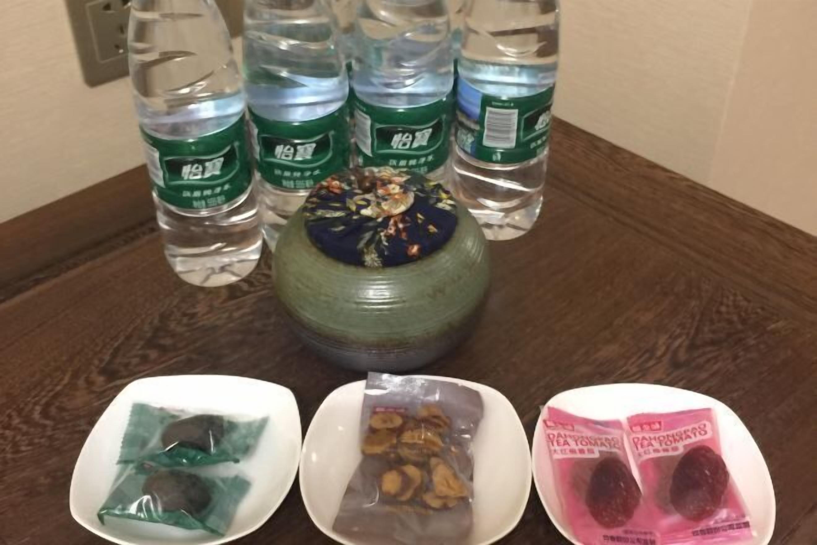 A table with bottled water, a decorative vase, and packaged snacks.