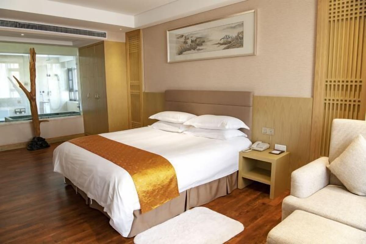 A hotel room with a bed, bedside table, and a chair.