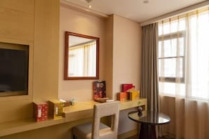 A hotel room with a wooden desk, a chair, a small round table, a mirror, and a window with curtains. - Richun Teaism Hotel (Quanzhou)