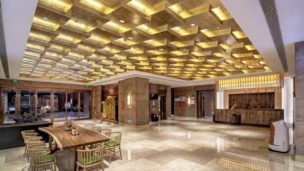 A spacious lobby with a wooden reception desk, seating area, and a patterned ceiling. - Richun Teaism Hotel (Quanzhou)