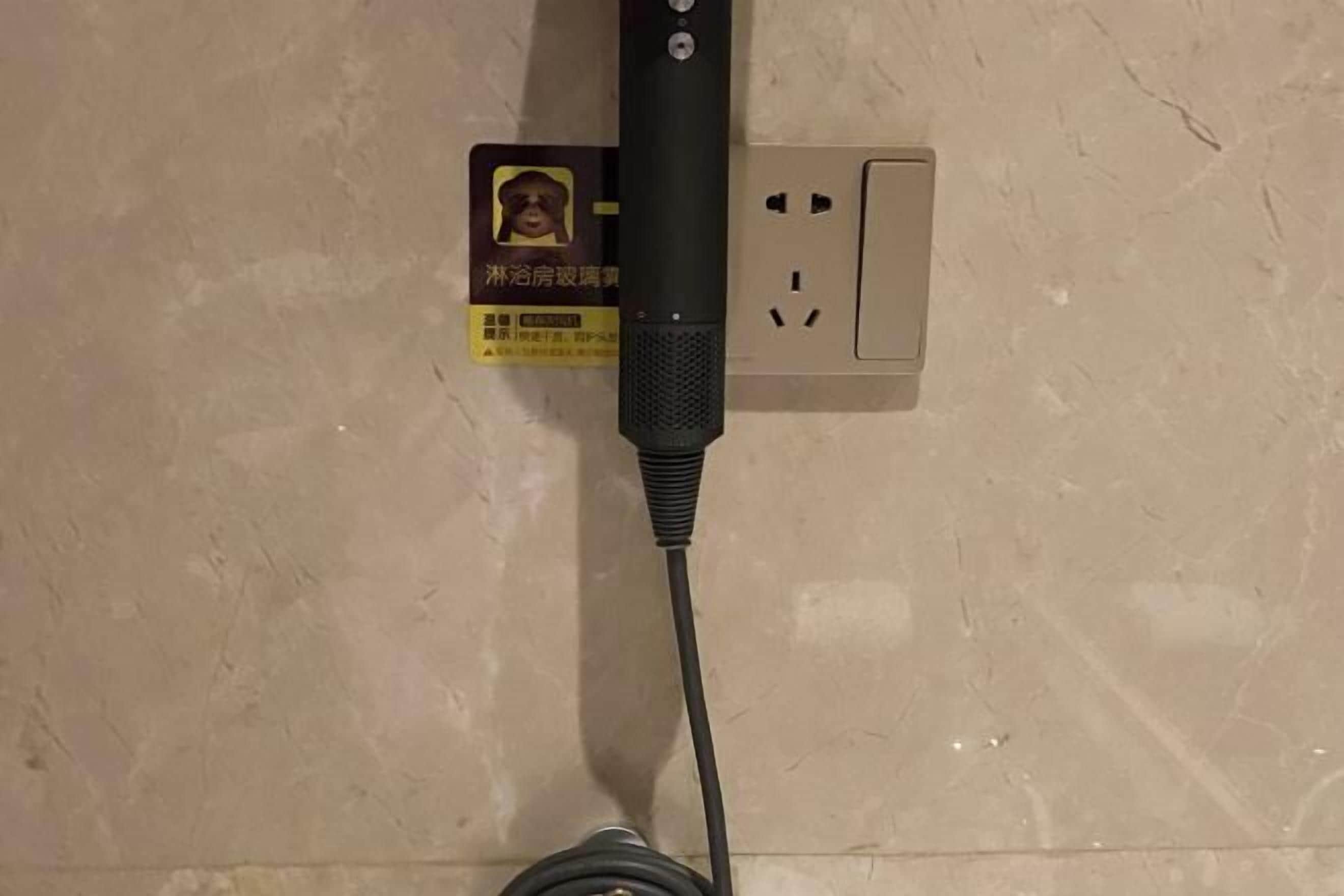 Een stekkerdoos met een aangesloten kabel, bevestigd aan een muur met een zichtbaar stopcontact.
