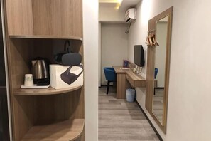A hotel room with a wooden vanity, a mirror, a desk with a chair, and a trash bin. - Guangzhou Xiguan Yuehua Hotel (Guangzhou)