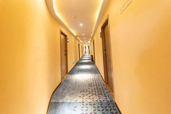 A hotel hallway with a patterned floor, doors on both sides, and a ceiling light. - Guangzhou Xiguan Yuehua Hotel (Guangzhou)