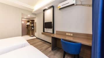 Habitación de hotel con dos camas, un escritorio, una silla, un televisor y un aire acondicionado.