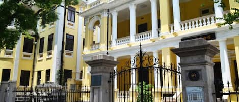 A yellow building with a central courtyard, columns, and a gated entrance.