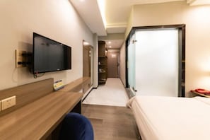 A hotel room with a bed, a desk, a television, and a wardrobe.