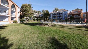 A hotel with multiple-story buildings, a swimming pool, and palm trees.