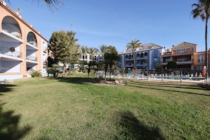 Um hotel com edifícios de vários andares, piscina e palmeiras.