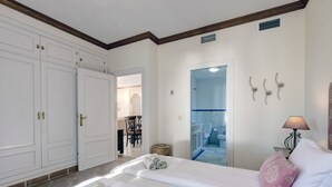 A hotel room with two beds, a bathroom, a dining area, and a hallway.