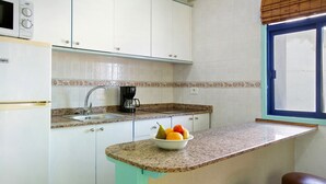 A kitchen with a sink, a microwave, a coffee maker, and a fruit bowl on the counter. - Mirra Apartment – Beach View (Puerto Rico)