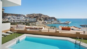 A rooftop pool with a view of a coastal town, buildings, and a mountain. - Mirra Apartment – Beach View (Puerto Rico)