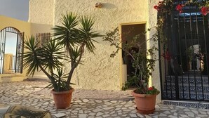 Ein Gebäude mit strukturierter Fassade, einem gefliesten Innenhof und Topfpflanzen.