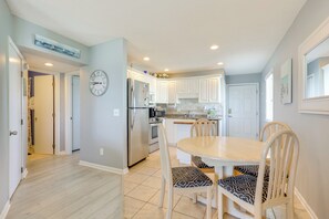 Una cocina moderna con armarios blancos, electrodomésticos de acero inoxidable y una zona de comedor con una mesa redonda y sillas estampadas.