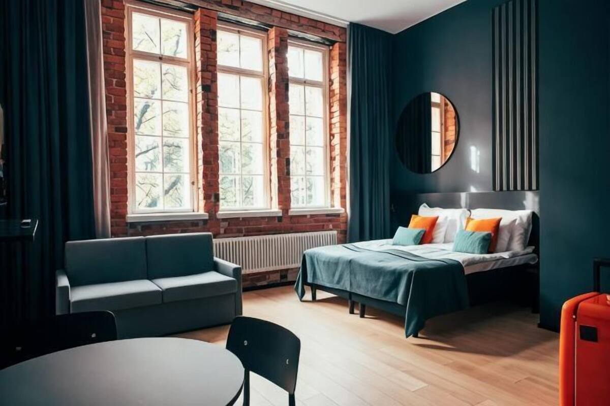 Una habitación con cama, sofá, mesa y ventana con vistas.