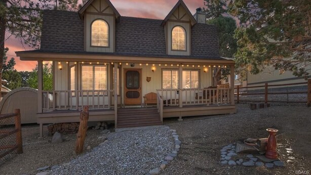 A two-story house with a porch, large windows, and a stone pathway leading to the entrance. - Hikers Haven - Close to Hiking, Fireplace, Horseshoes, Deck, BBQ (Big Bear City)