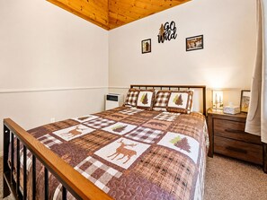 A bedroom with a bed, a nightstand, a wall-mounted heater, and a 'GO Wild' sign.