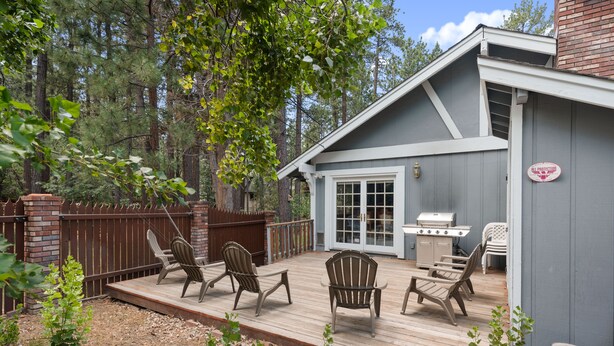 A deck with Adirondack chairs, a grill, and a patio table.