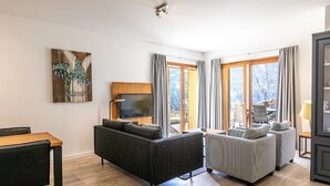 A modern living room with a sofa, armchairs, a TV, and a painting on the wall. - Modern Mountain Stay (Abondance)