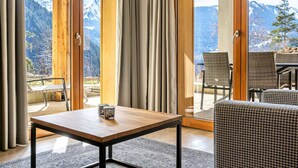 A room with a wooden table and chairs, large windows with curtains, and a view of snow-capped mountains. - Modern Mountain Stay (Abondance)