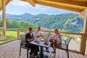 A wooden deck with a table and chairs, overlooking a mountainous landscape. - Modern Mountain Stay (Abondance)