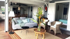 Un'accogliente zona living con divano, poltrone in vimini, tavolino da caffè e zona pranzo con sedie e tavolo.