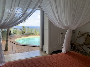 A bedroom with a view of a swimming pool and a balcony. - Beautiful Villa with Sea View & Pool - Relaxing stay in the tropics (Deshaies)