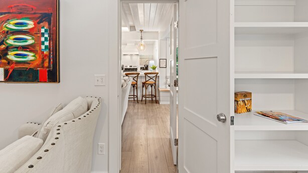 Un couloir avec une porte blanche donnant sur un espace cuisine.