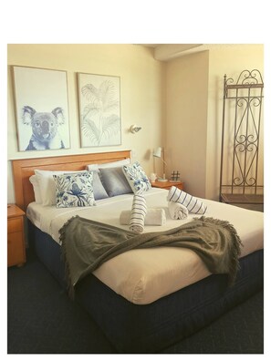Cozy retreat with a neatly made bed, wooden nightstand, and framed artworks.