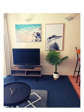 Relax in this stylish living room with a flat-screen TV, framed artworks, and a potted plant.