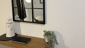 A room with a wooden desk, a white lamp, a small white lighthouse model, and a mirror with a black frame. - The Howff - Lovely 2-bed Apartment in Anstruther (Anstruther)