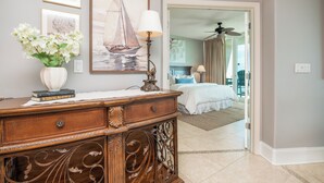 A bedroom with a bed, a dresser, a vase with flowers, and a sailboat painting on the wall.