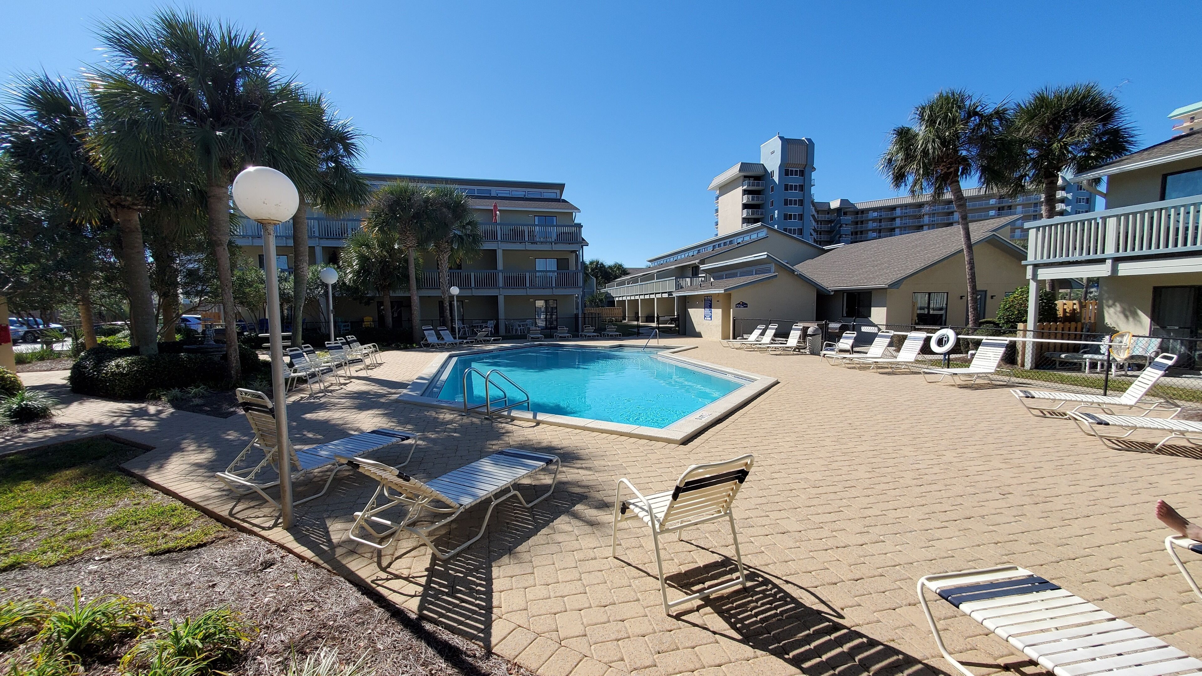A pool area with lounge chairs and a clear blue pool surrounded by buildings.