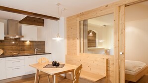 A compact kitchen with white cabinets, a wooden dining table, and a built-in bench. - Unwind - relax - seek peace - enjoy - Merano is my holiday destination (Meran)
