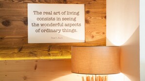 A framed quote on a wooden wall, a lamp, and a wooden bench. - Unwind - relax - seek peace - enjoy - Merano is my holiday destination (Meran)