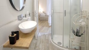 A modern bathroom with a round mirror, a white sink, and a glass-enclosed shower. - 2 Rooms at the Colosseum Rome New Apartment (Roma)