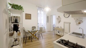 A modern kitchen with a gas stove, a dining area with a glass table and chairs, and a white interior. - 2 Rooms at the Colosseum Rome New Apartment (Roma)