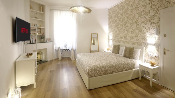 A bedroom with a bed, bedside tables, a TV mounted on the wall, a wardrobe, and a window with curtains. - 2 Rooms at the Colosseum Rome New Apartment (Roma)