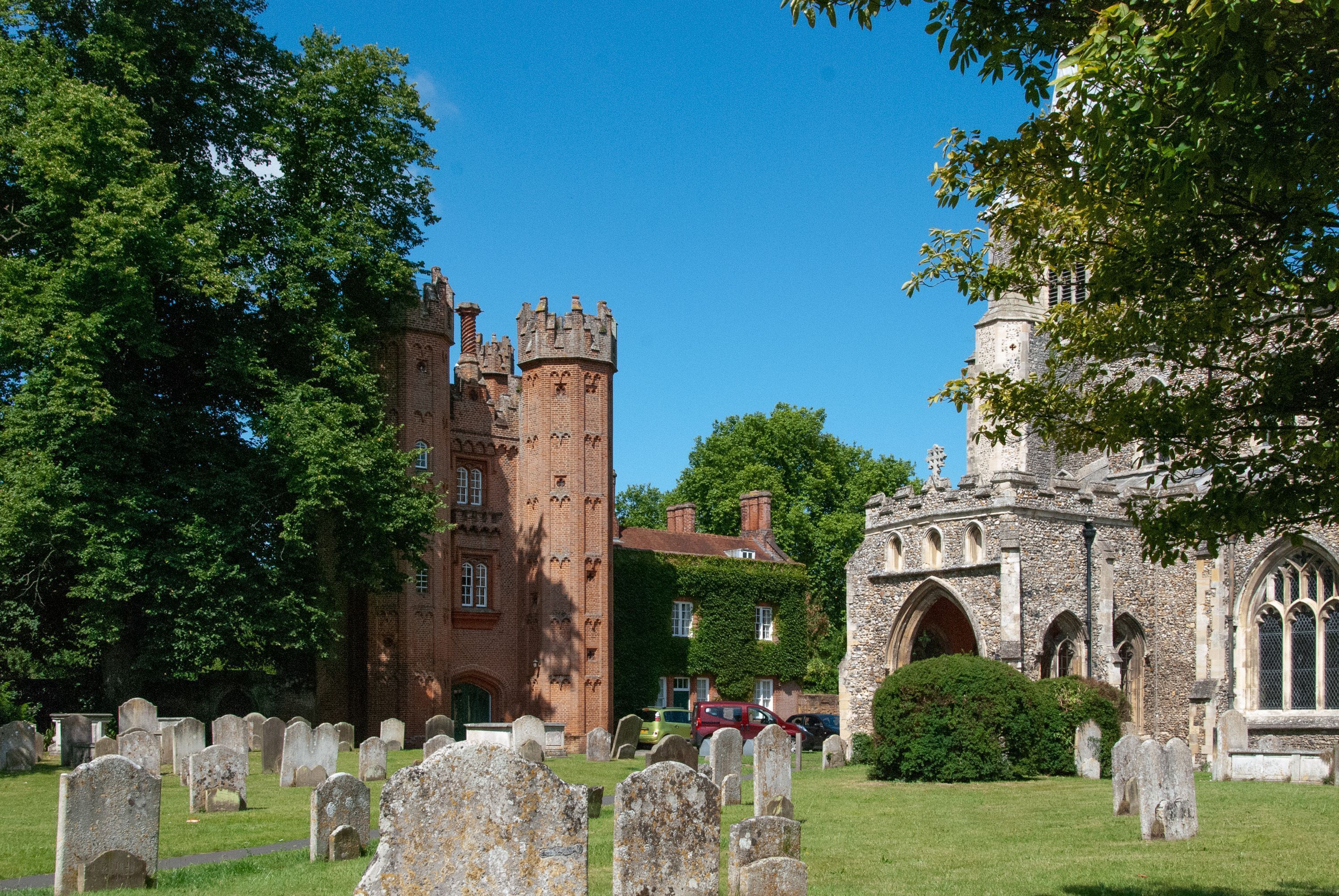 A historic building with a prominent tower and arched windows, surrounded by a cemetery with headstones.