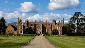 A large, historic building with a symmetrical facade, multiple chimneys, and a central entrance. - A romantic little Flax Workers Cottage with a beautiful open fire and an enclosed garden which leads (Long melford)