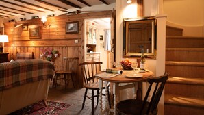 A cozy room with a bed, a wooden dining table, chairs, and a large mirror. - A romantic little Flax Workers Cottage with a beautiful open fire and an enclosed garden which leads (Long melford)