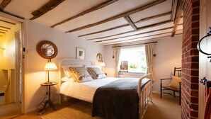A bedroom with a bed, bedside lamps, a mirror, and a window with curtains. - A romantic little Flax Workers Cottage with a beautiful open fire and an enclosed garden which leads (Long melford)