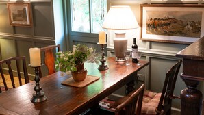 Une table à manger en bois, décorée de bougies, d’un vase rempli de fleurs et d’une lampe.
