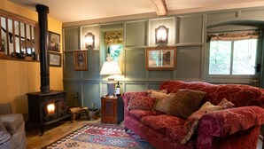 Un salon chaleureux avec un canapé rouge, un tapis à motifs et un poêle à bois.