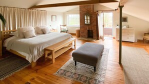 A bedroom with a large bed, a bench, a fireplace, and a view of the outdoors. - Five Star style with beautiful views of idyllic Countryside: The Old Steam Mill (Hartest)