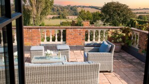 A patio with wicker furniture and a view of the countryside. - Five Star style with beautiful views of idyllic Countryside: The Old Steam Mill (Hartest)