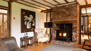 Una sala de estar acogedora con una chimenea de ladrillo, un sillón cómodo y un televisor de pantalla plana.