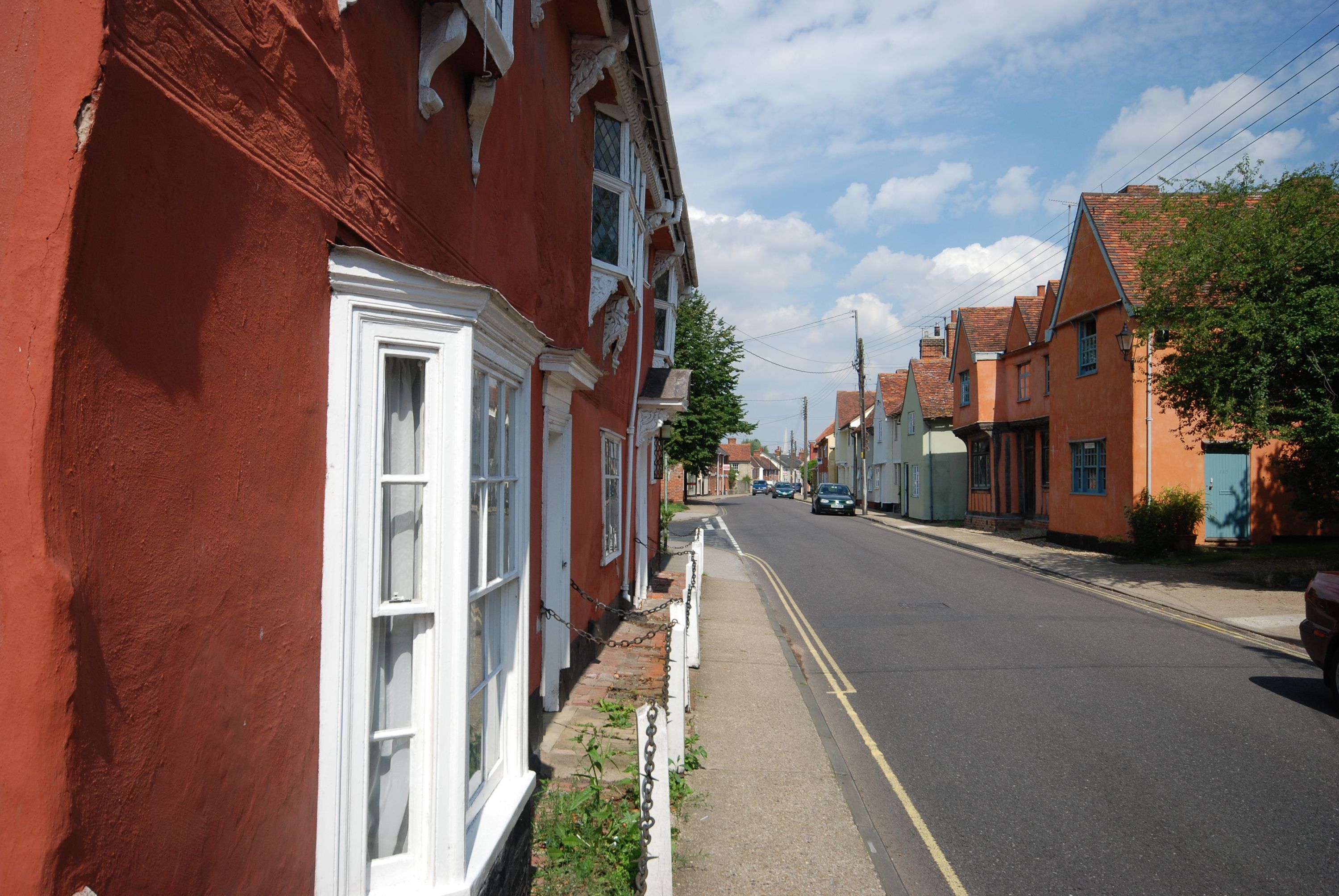 Une rue bordée de maisons rouges et oranges, avec un trottoir et une chaussée.