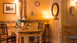 A wooden dining table with chairs, a vase with flowers, a wine bottle, and a candle. - Quirky little Bolt-Hole, bags of character by a Historic Town with lovely walks (Hadleigh)